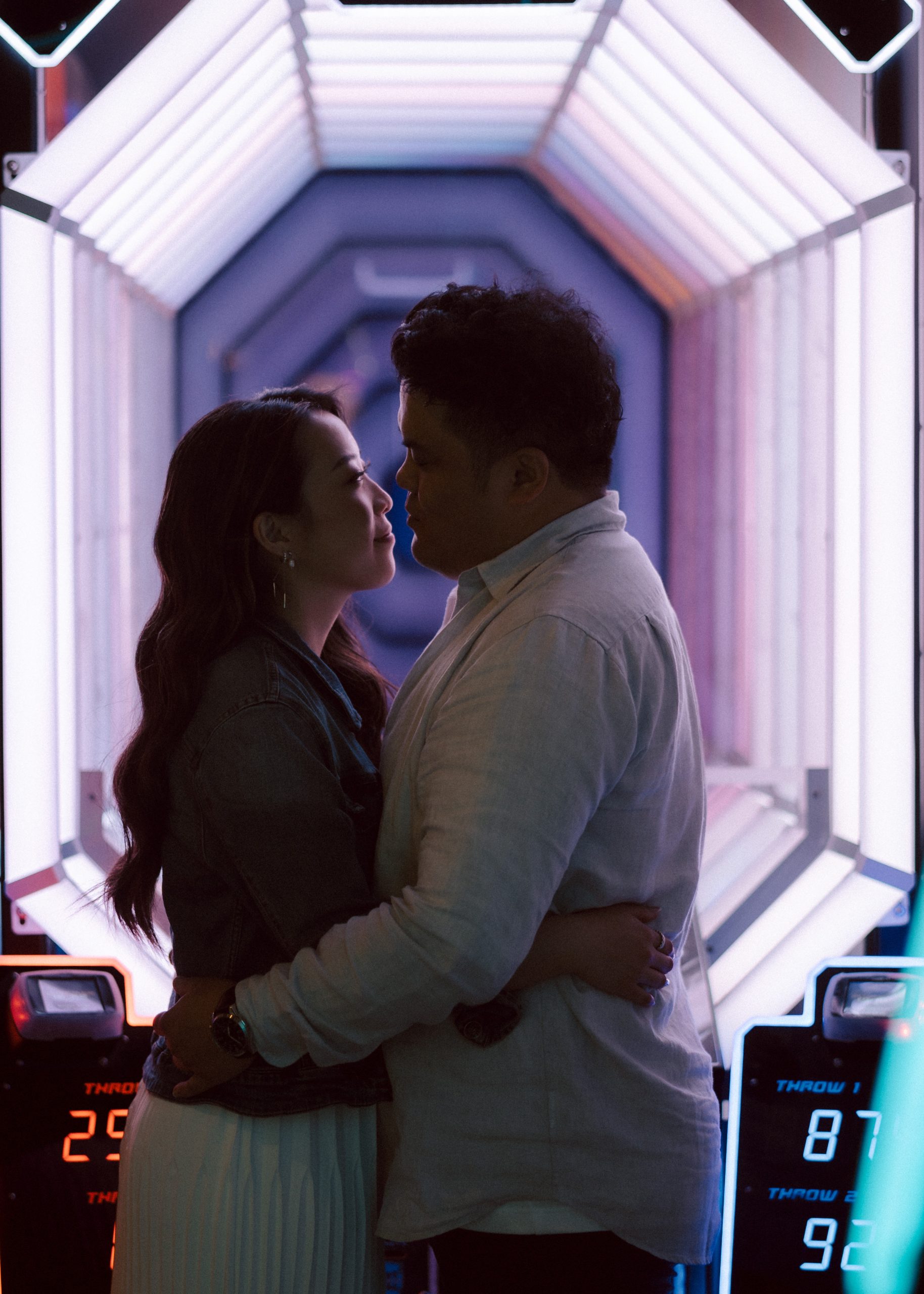 Couple surrounded by pink, blue and purple neon lighting.