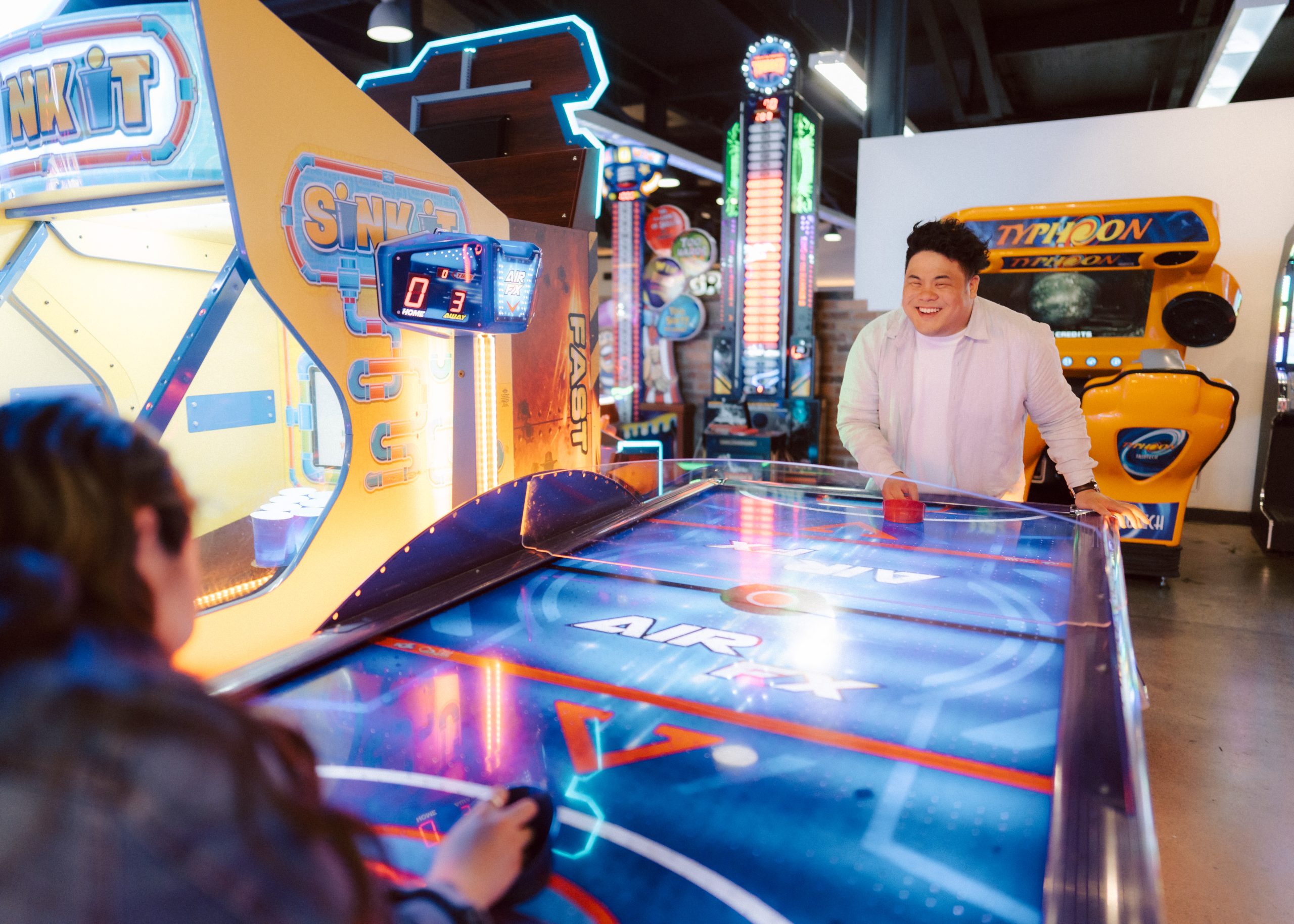 Couple in an arcade playing air hockey.